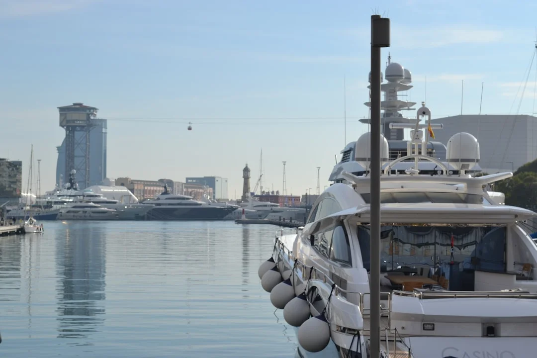 Sailing yacht stern-to at a Mediterranean marina with a coastal city in the background