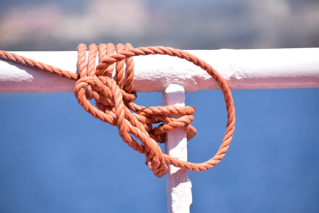Nautical rope tied securely to a metal cleat on a sailboat, demonstrating docking knot technique