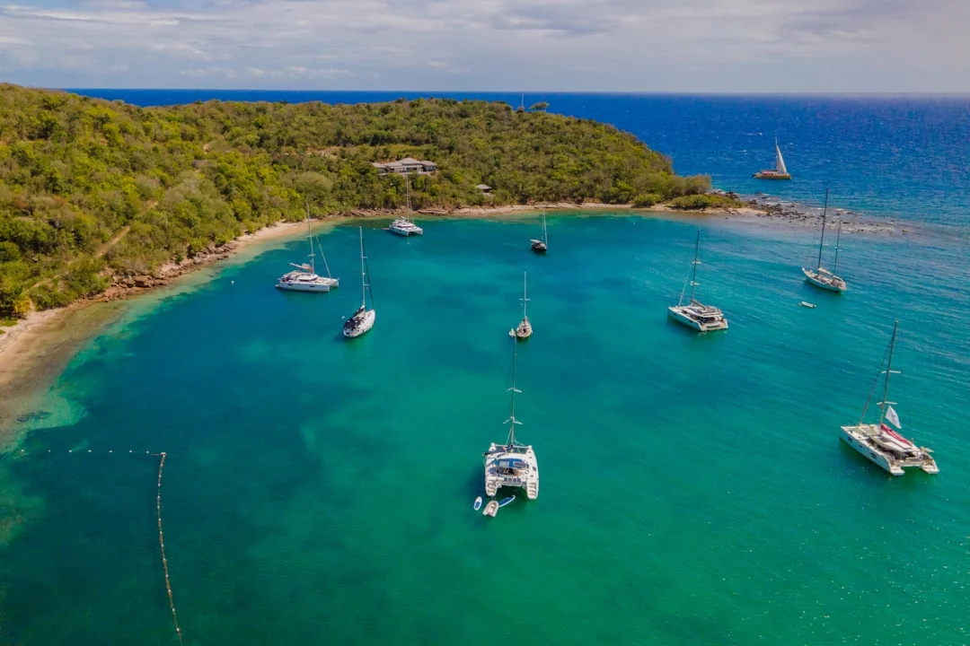 Sailboats anchored in a sheltered turquoise bay with tropical hills in the background