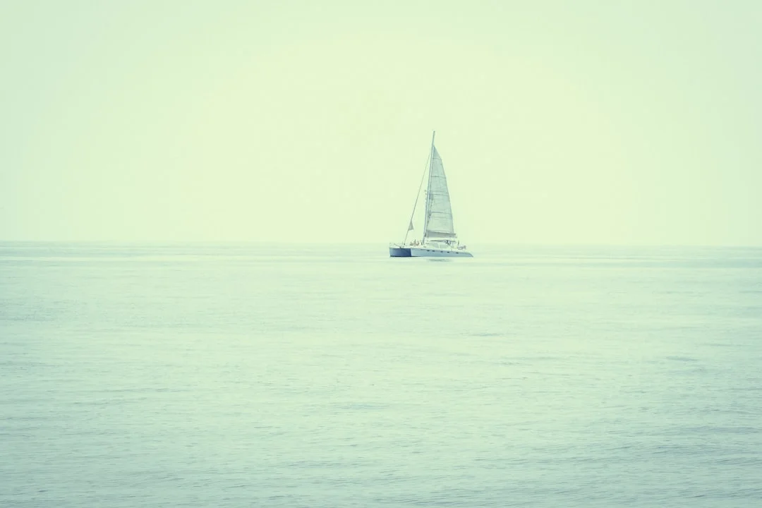 Sailboat silhouette on a calm misty sea at dawn