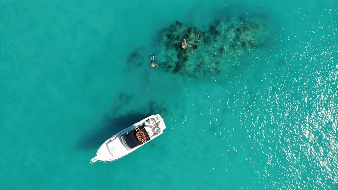 Boat and swimmers in clear turquoise water at anchor