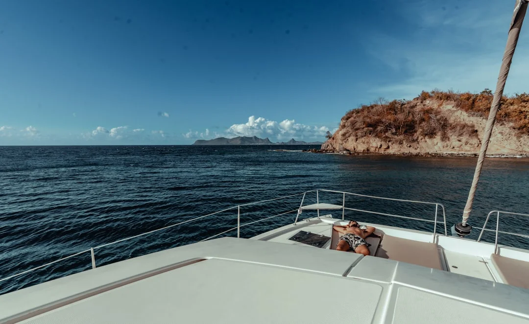 Catamaran sailing toward a rocky island on calm blue sea