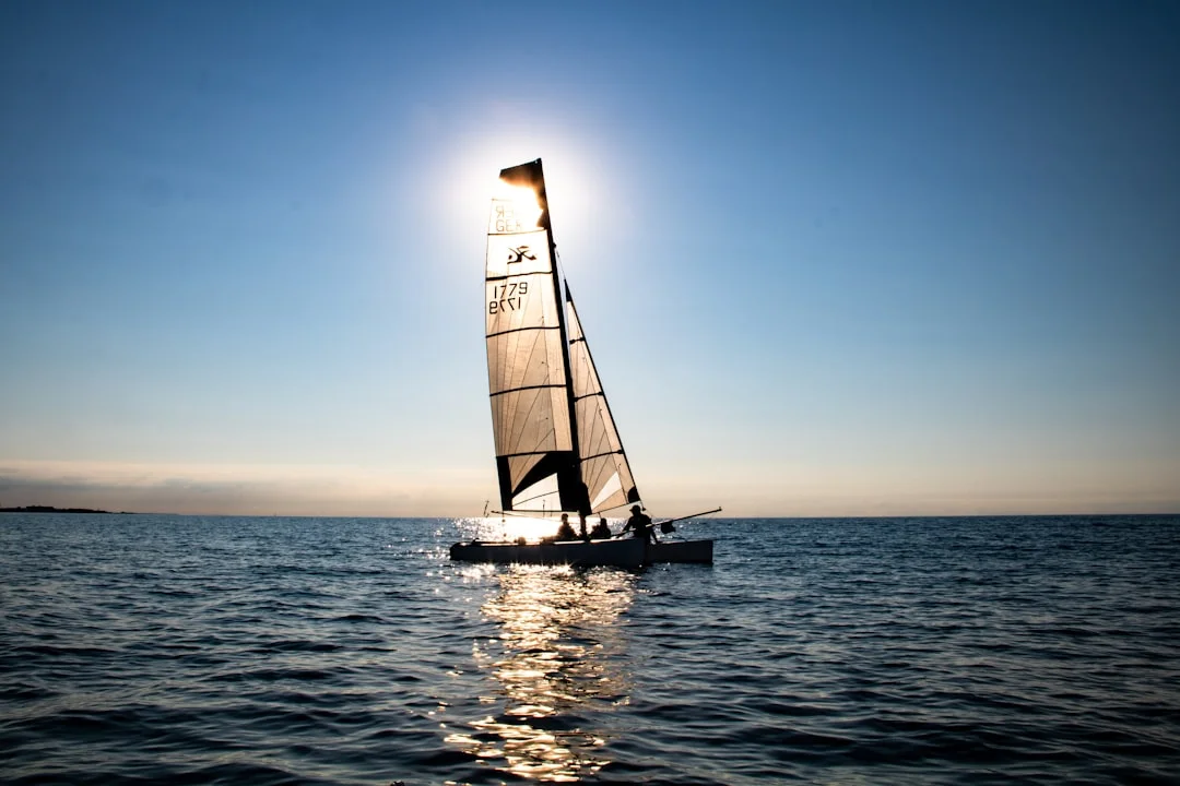 Sailboat sailing toward the sun on open water
