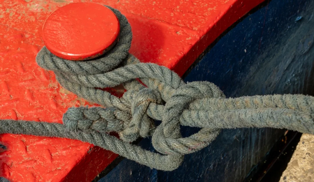 Rope secured to a wooden dock post with a cleat hitch knot, a fundamental sailing knot