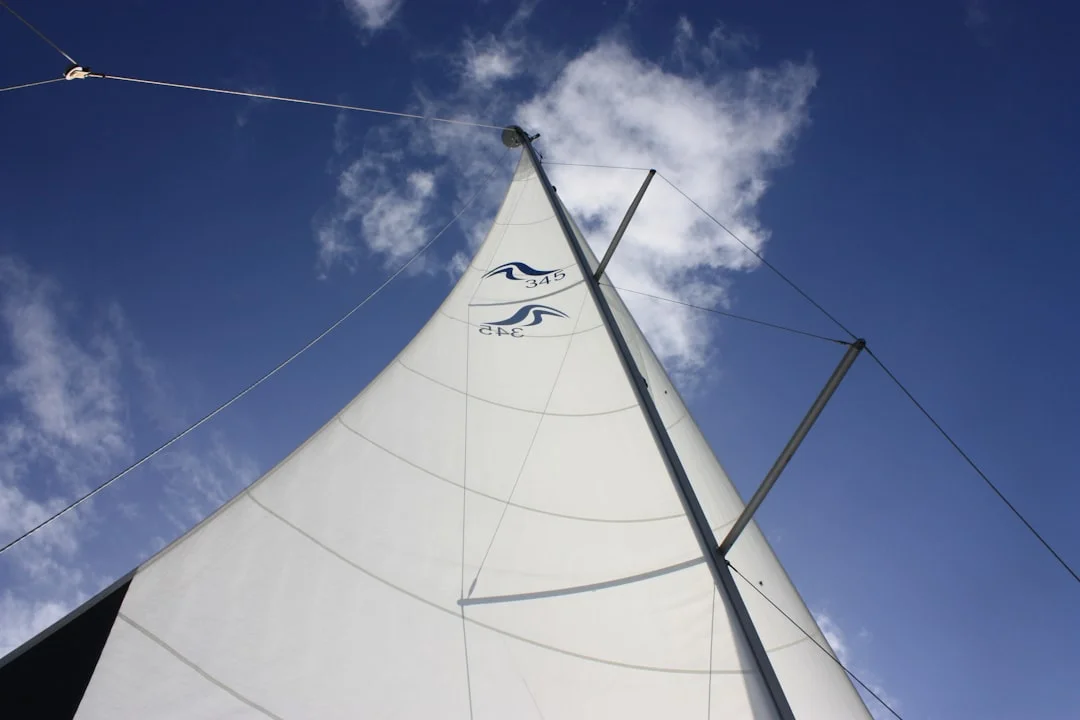 White sailing boat moving through open water with sails set for windward course