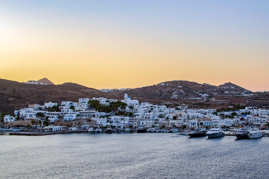 Sunset over the harbor of Milos Island in Greece with colorful hillside buildings