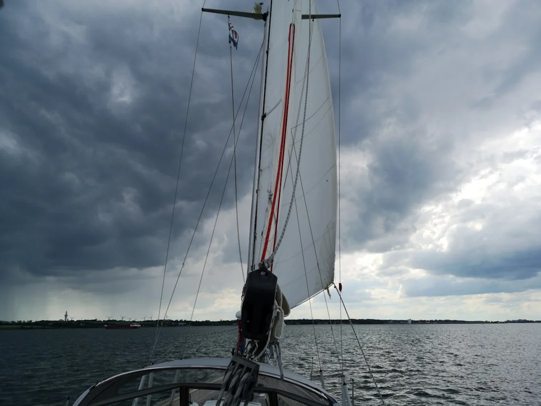 Sailing yacht approaching coastline under white sails on open water