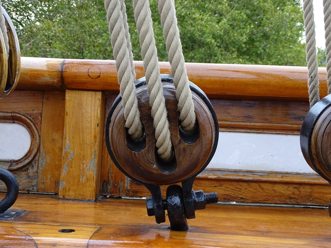 Wooden block and tackle rigging on a sailboat deck with ropes running through pulleys