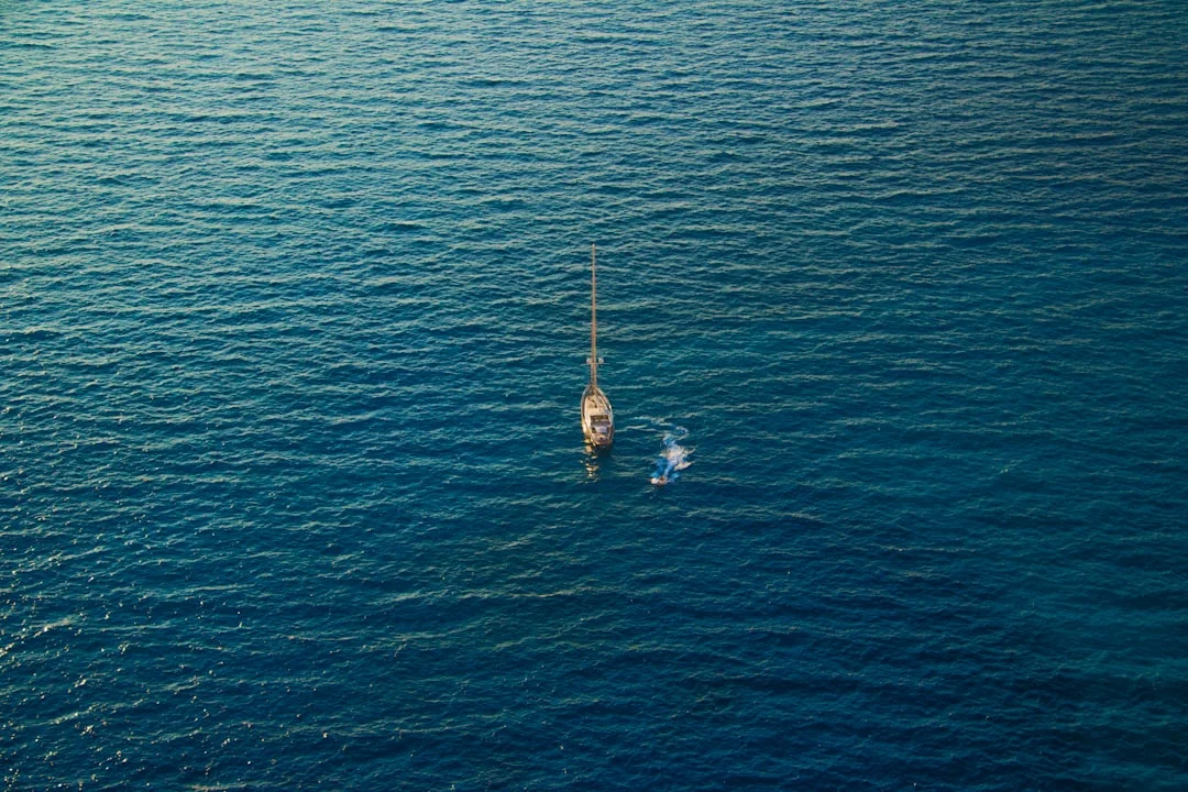 Sailing yacht crossing open ocean waters under clear sky