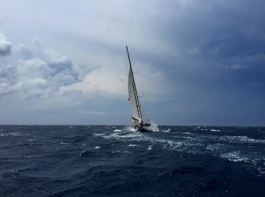 Sailboat heeling under dark storm clouds with wind building on open water