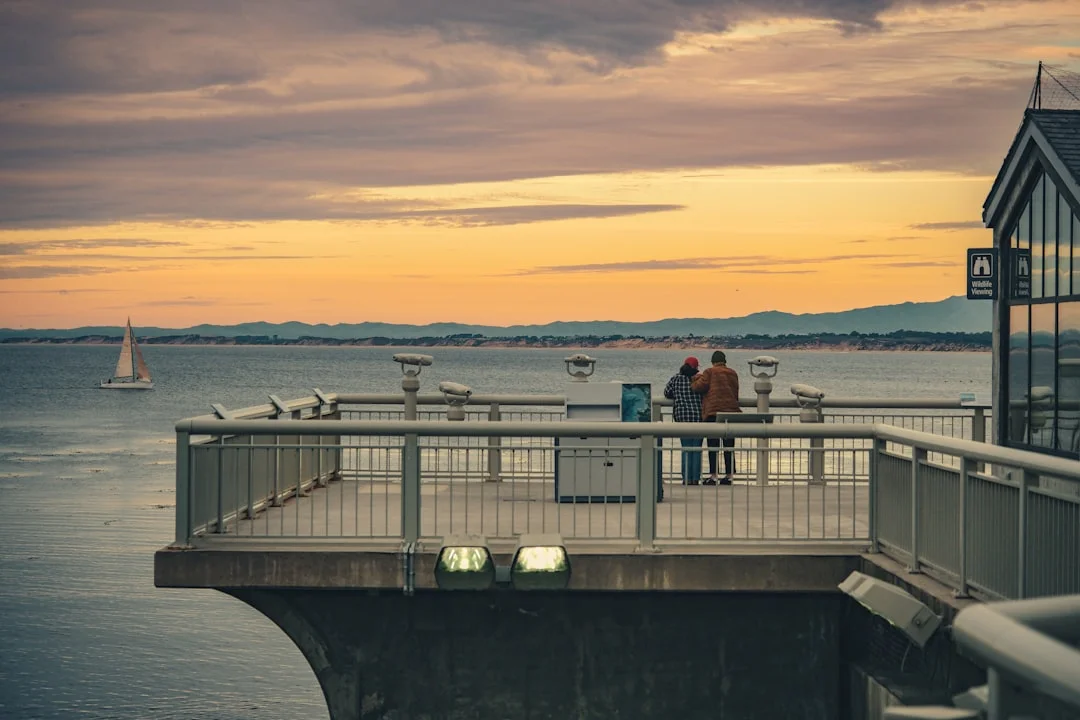 Couple watching a sailboat at sunset from shore