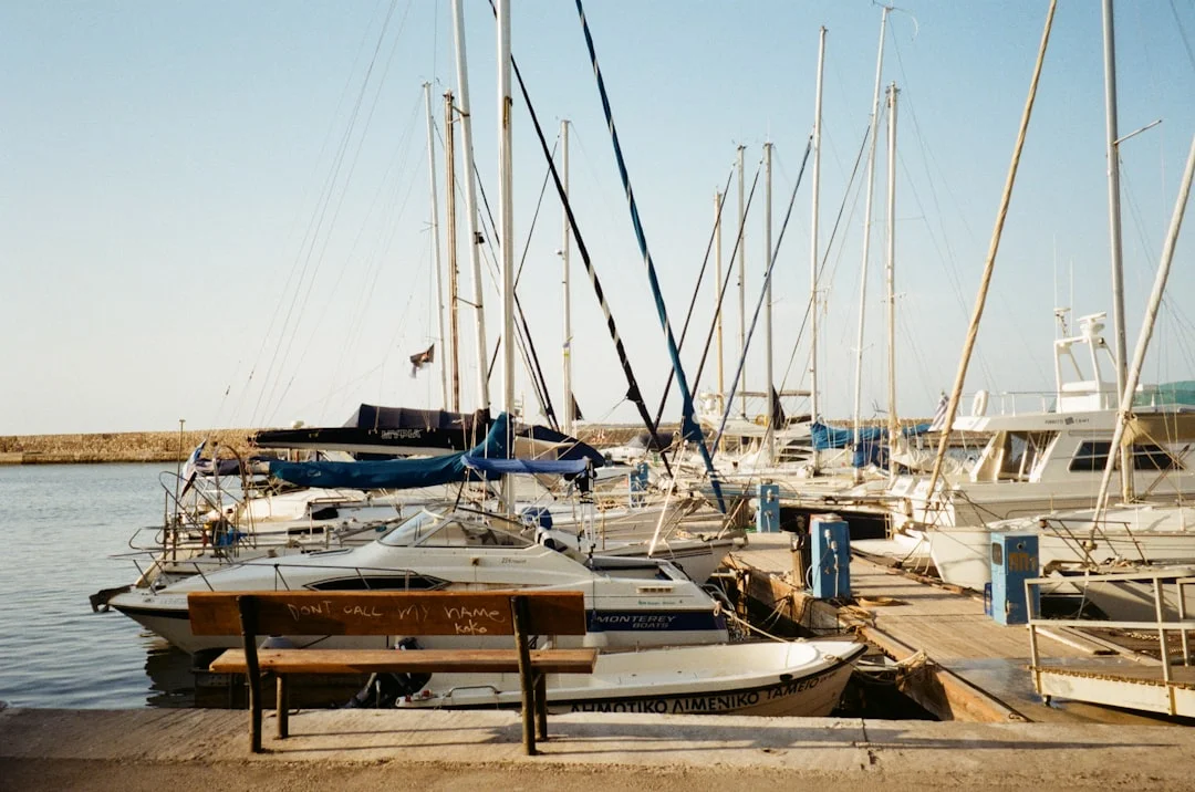 White sailing boats lined up alongside a harbour dock on a sunny day