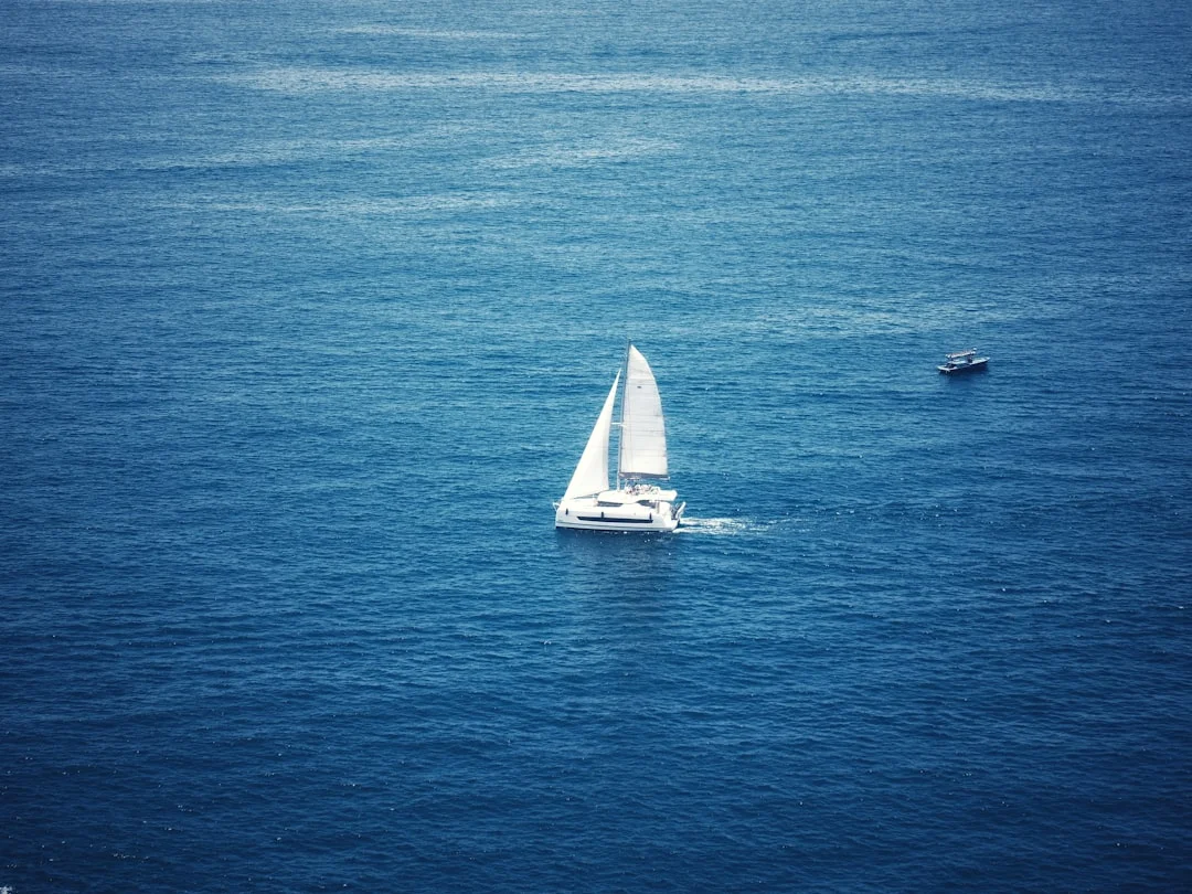 White sailboat gliding across deep blue ocean on a passage