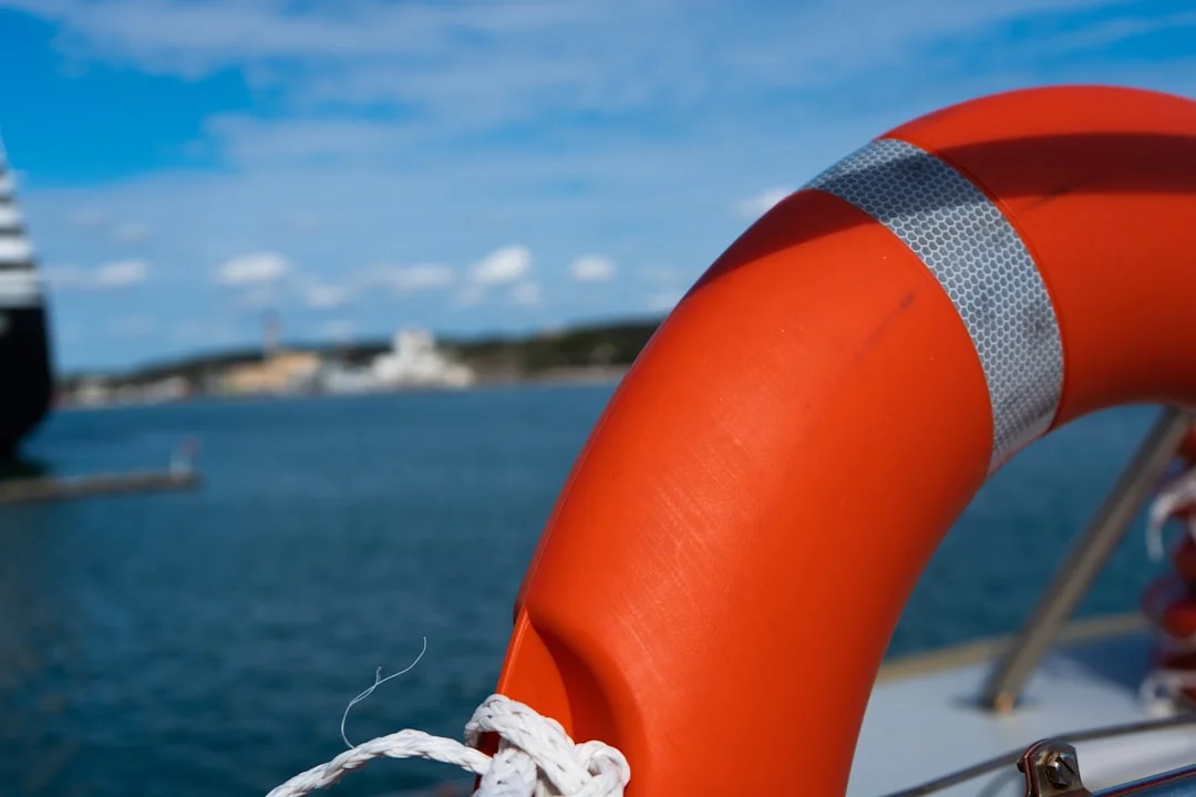 Orange life preserver mounted on a boat with calm water in the background