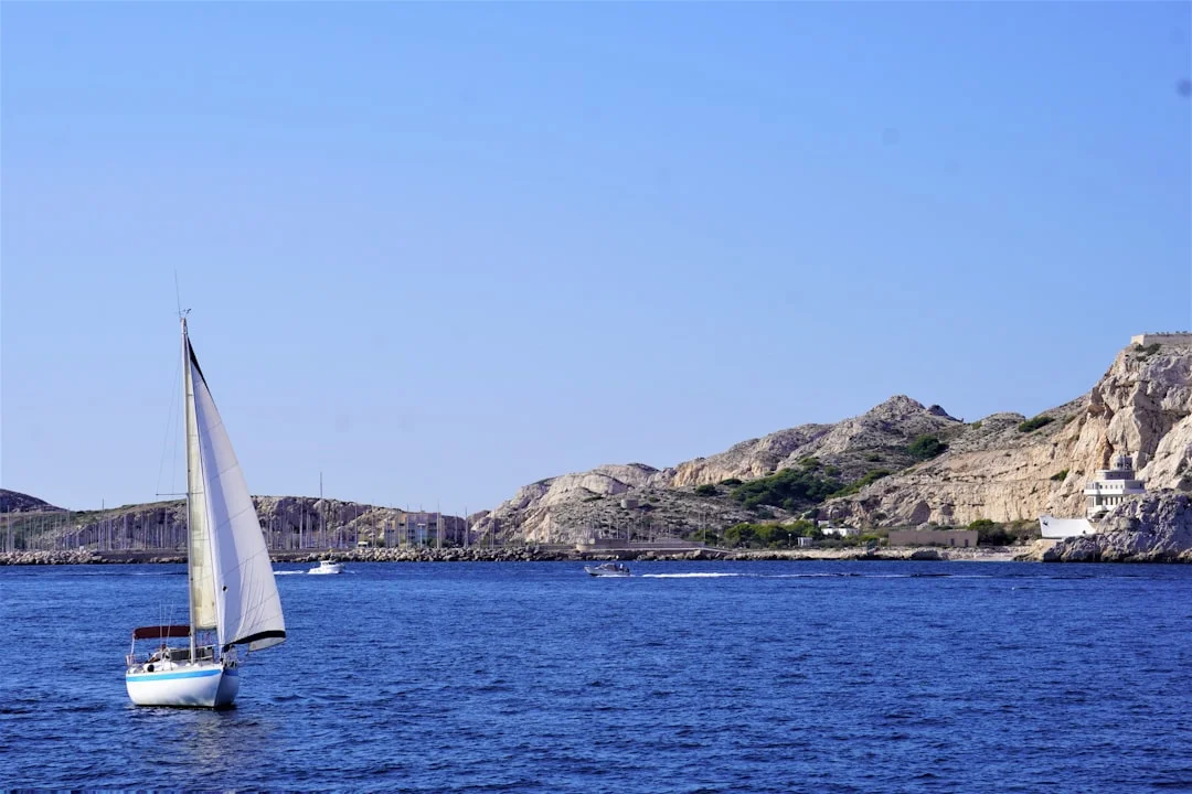 A sailboat moored in a Mediterranean bay with dramatic mountain scenery in the background