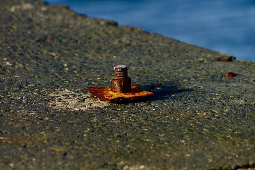 Close-up of a stainless swage terminal with rust weeps under strong side lighting