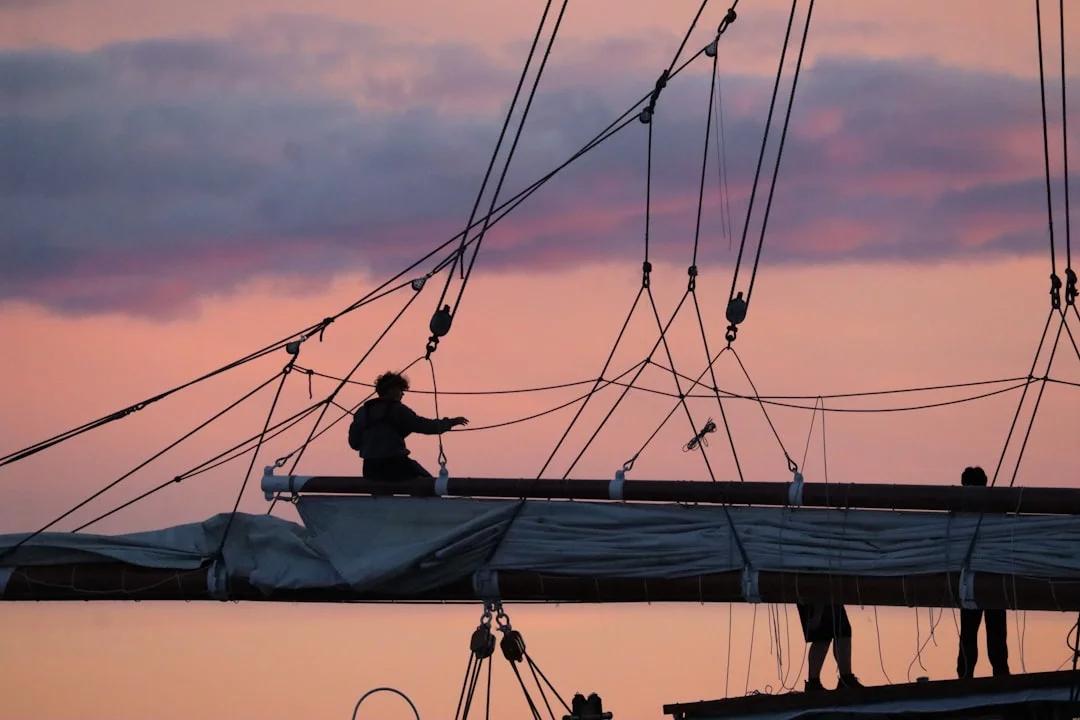 Sailing crew working together on deck of a sailboat at sunset
