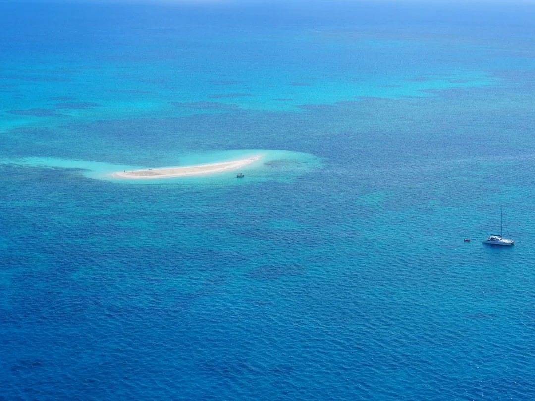 Yacht at anchor next to a reef-ringed island in the Coral Sea
