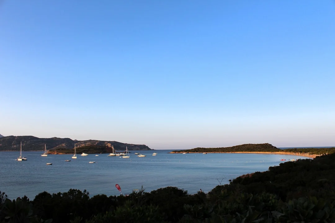 Sailboats anchored in a calm turquoise bay off the coast of Sardinia, Italy