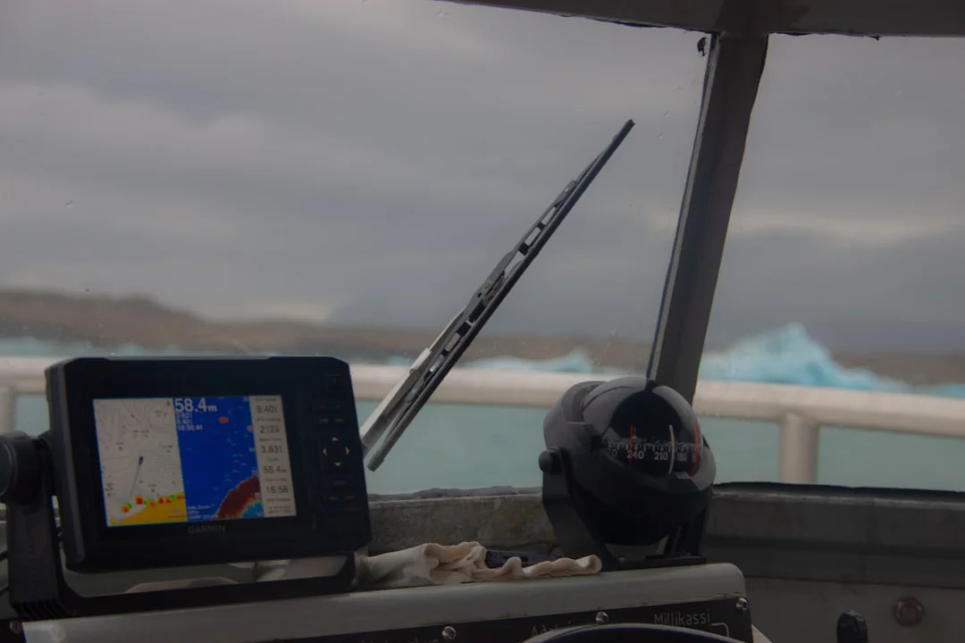 Tablet at helm showing ENC-based chart with AIS targets; secondary phone running Windy for big-picture weather