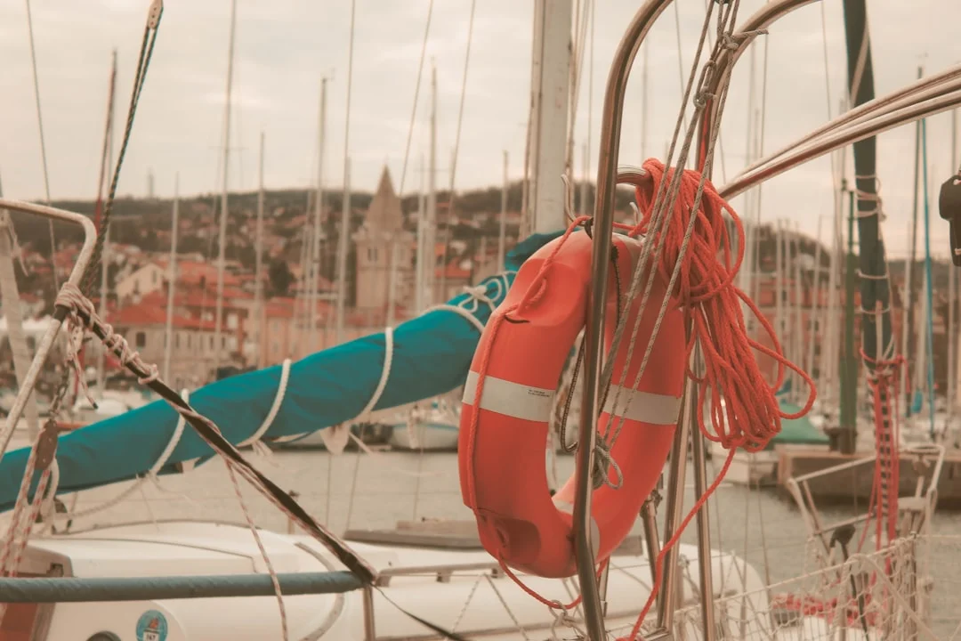 Orange and white life ring tied to sailboat railing with ocean in the background