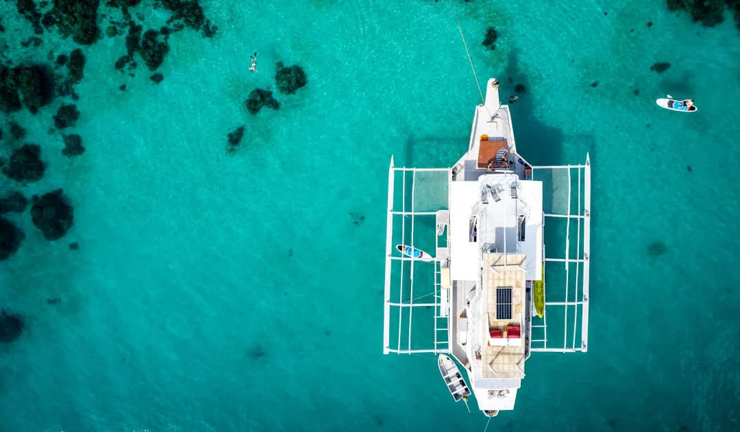 Aerial view of a catamaran anchored in turquoise tropical waters with spacious deck and solar panels