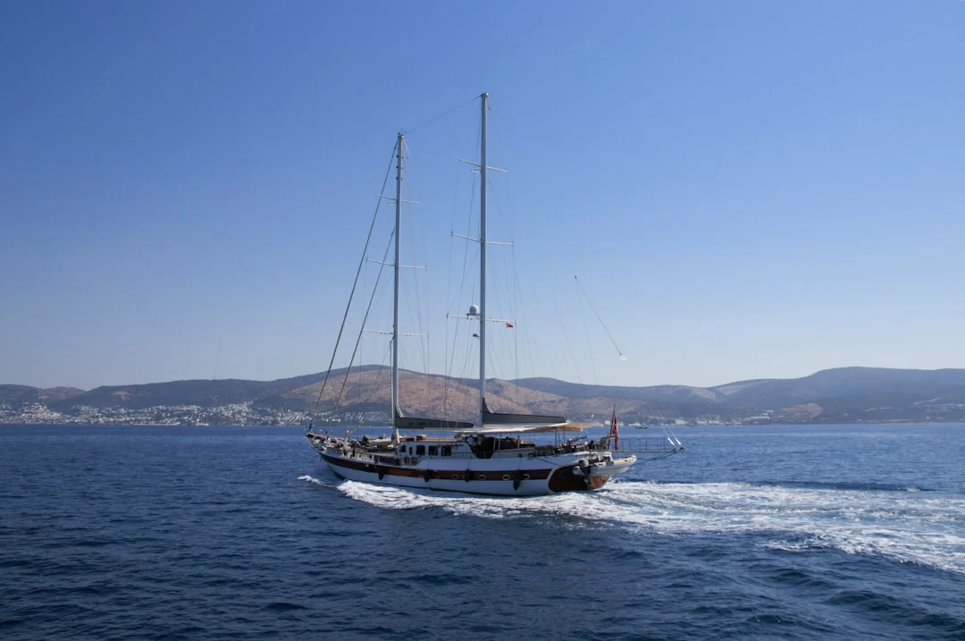 Cruising keelboat sailing with mountain backdrop