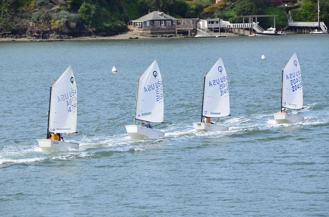 Four sailing dinghies racing across the water - dinghy vs keelboat comparison