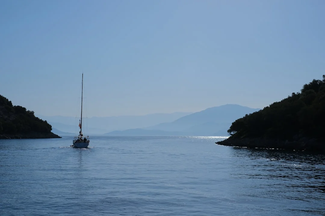 A cruising sailboat under headsail on calm water
