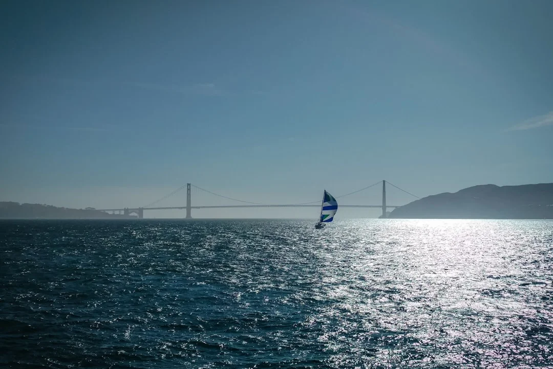 Cruising sailboat with blue and yellow sails on calm sea