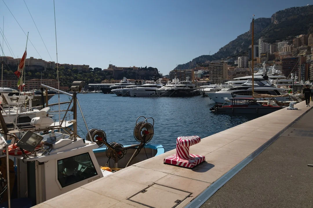 A stern-to Mediterranean marina scene showing fingerless quay, boats backed in, and lazy line pickup points on the dock