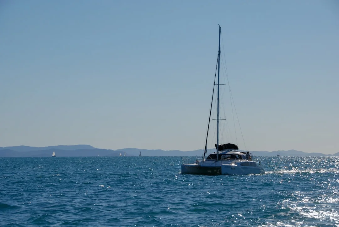 Sailboat anchored beneath green island peaks in the Whitsundays