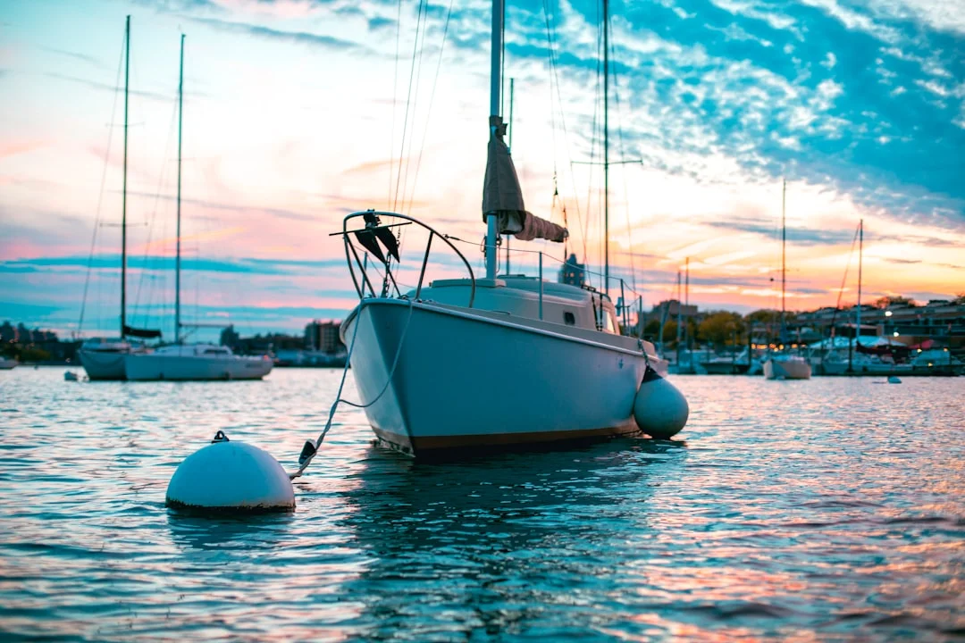 White sailing boats lined up alongside a harbour dock on a sunny day