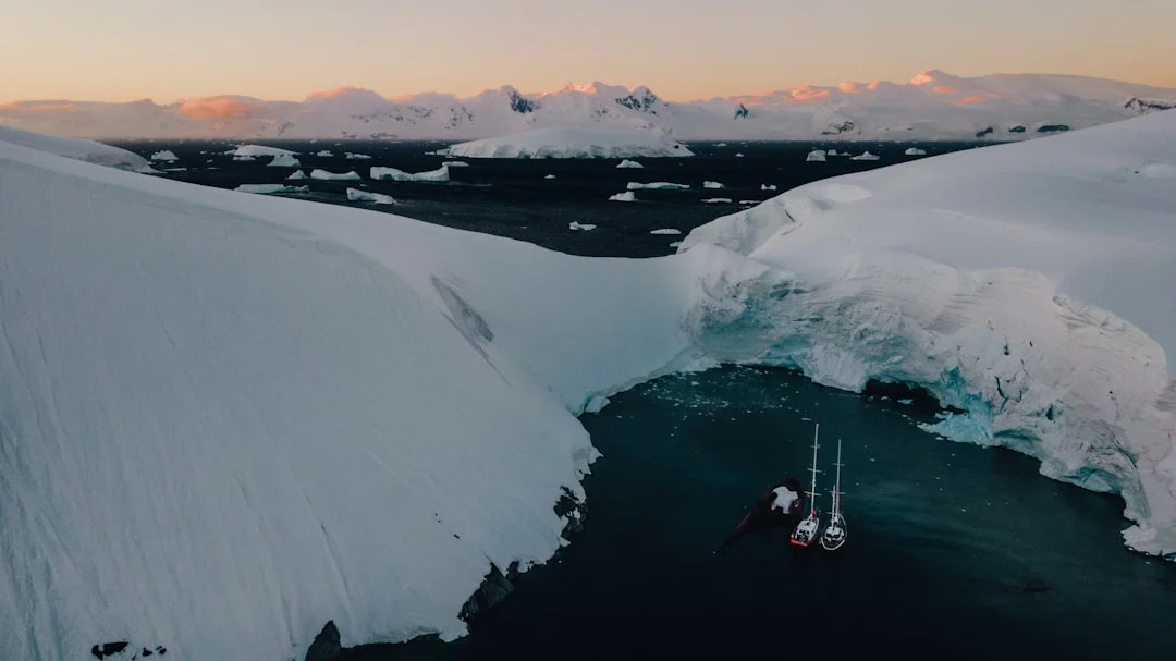 Boat cruising among giant icebergs in the Antarctic Peninsula