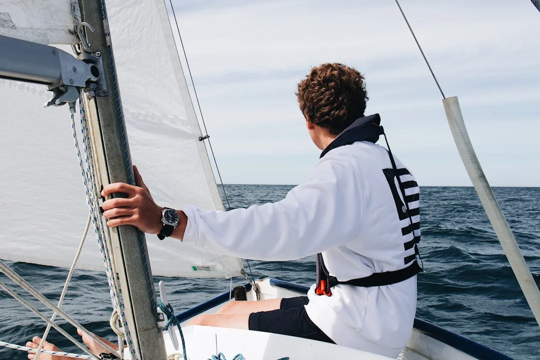 A wet-gloved hand pressing large watch buttons at the helm, spray visible