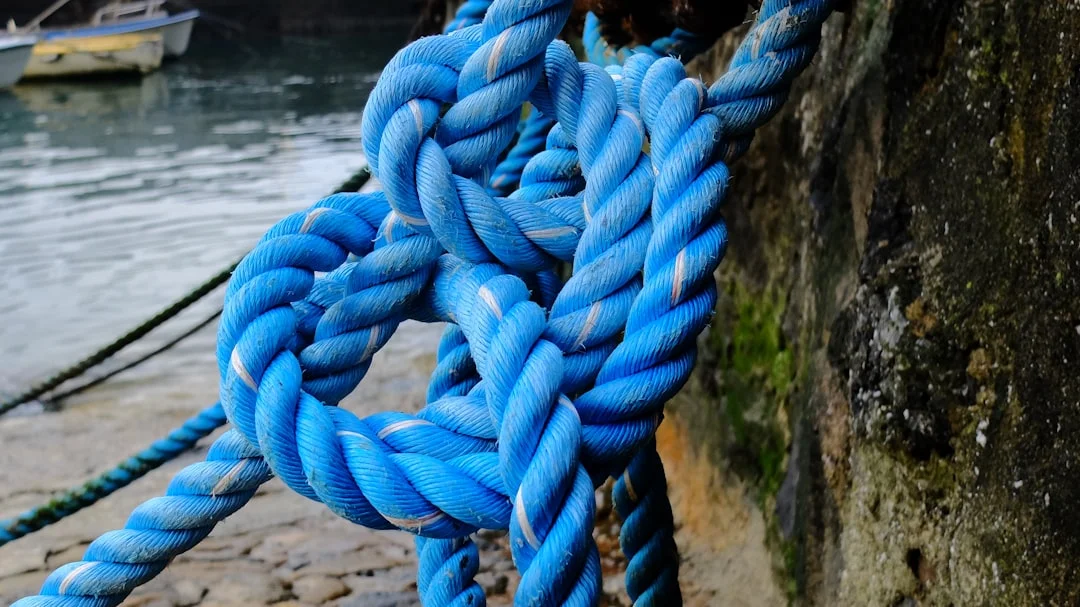 Nautical rope tied securely to a metal cleat on a sailboat, demonstrating docking knot technique