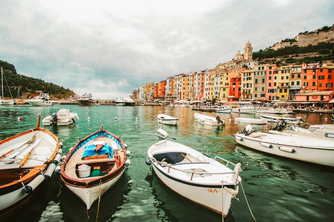 Two boats moored near towering sea cliffs along the Italian coastline