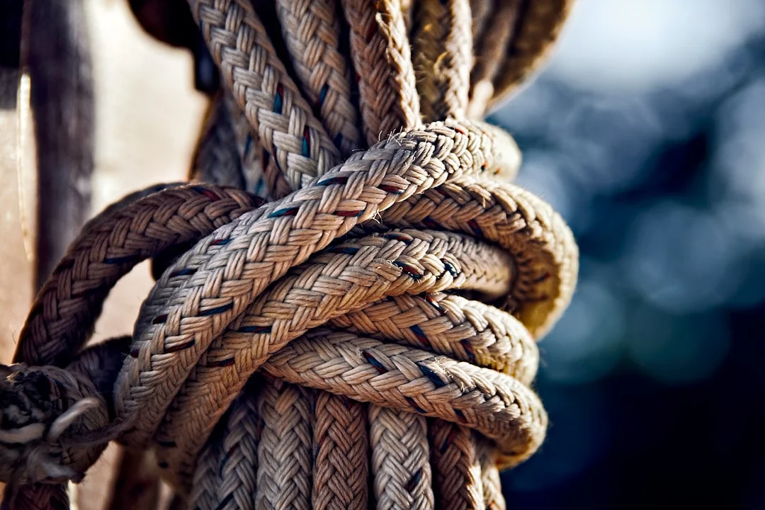 Rope secured to a wooden dock post with a cleat hitch knot, a fundamental sailing knot