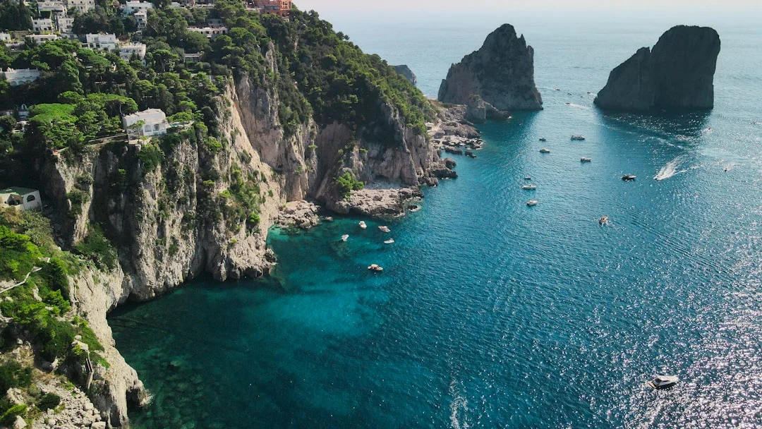 A sailing boat cruising along the Amalfi Coast with colorful cliffside villages in the background