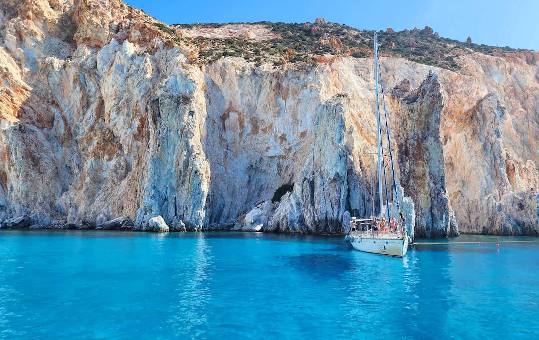 Whitecaps in a Cyclades channel with a reefed mainsail and ferry wake in the distance