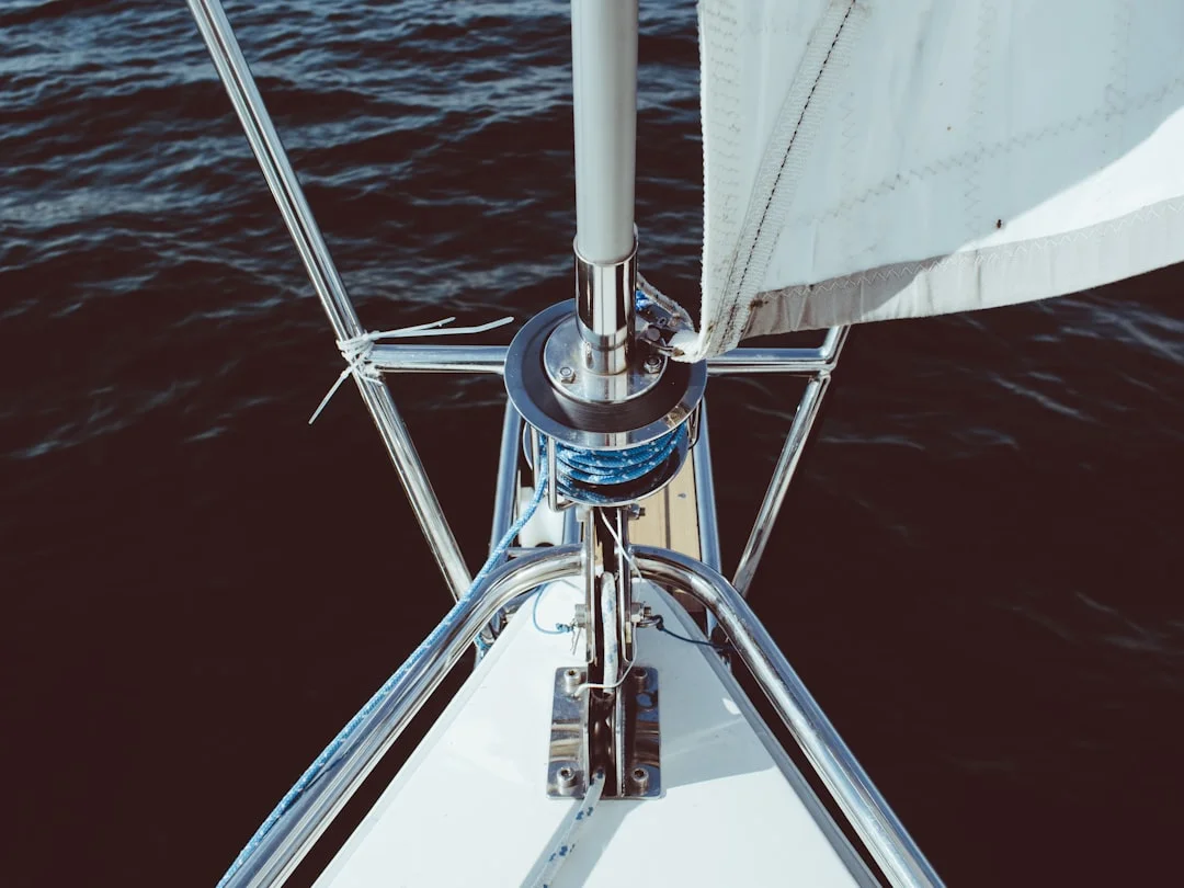 Sailing yacht stern-to at a Mediterranean marina with a coastal city in the background