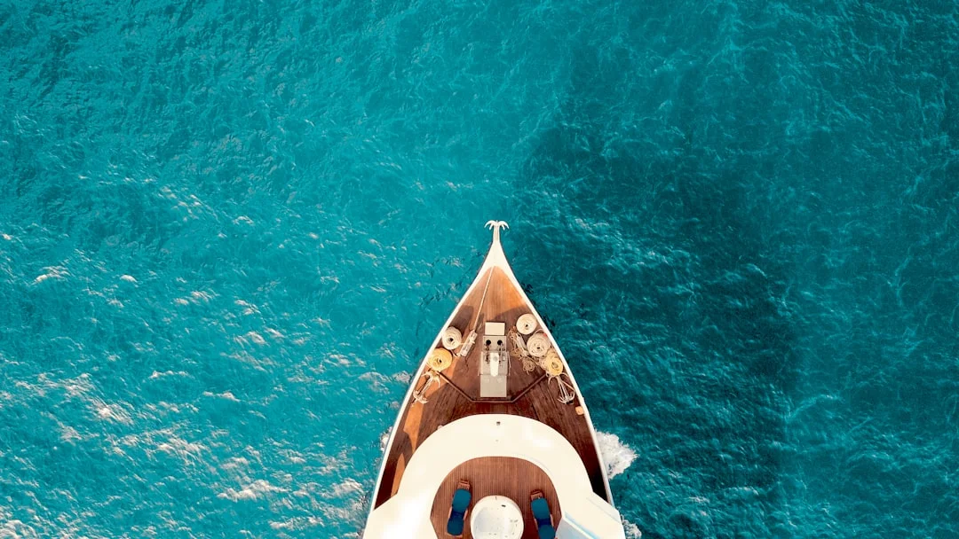 A crewed sailing catamaran anchored off a Mediterranean cala at golden hour