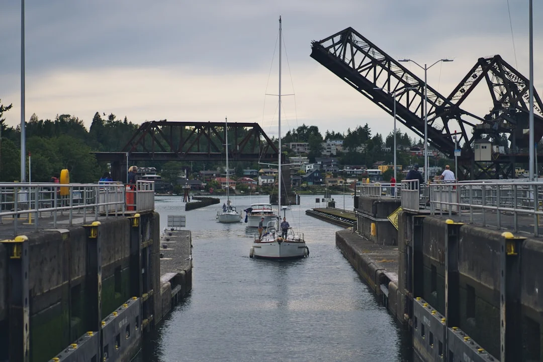 A mid-size cruising sailboat secured in a lock with floating bollards, fenders deployed along the lock wall