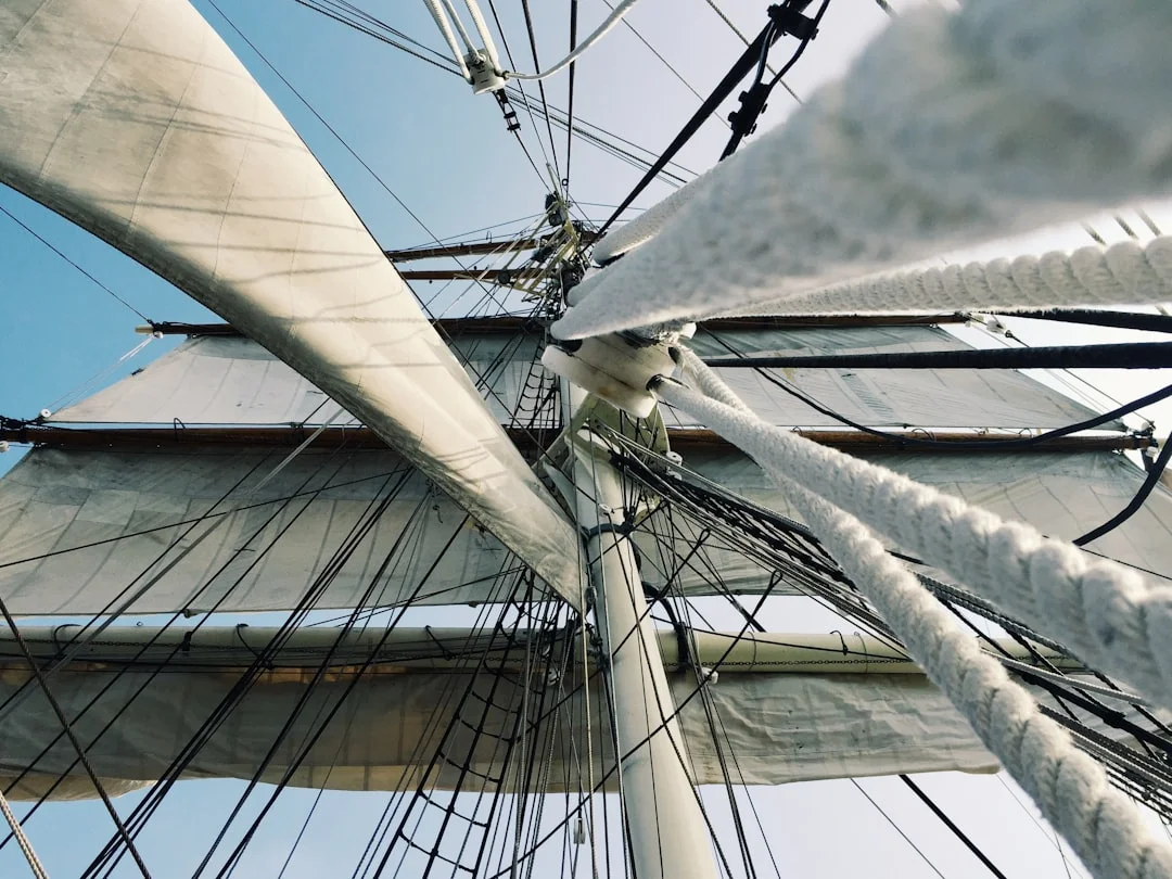 Rigger in bosun’s chair inspecting masthead sheaves and halyard exits