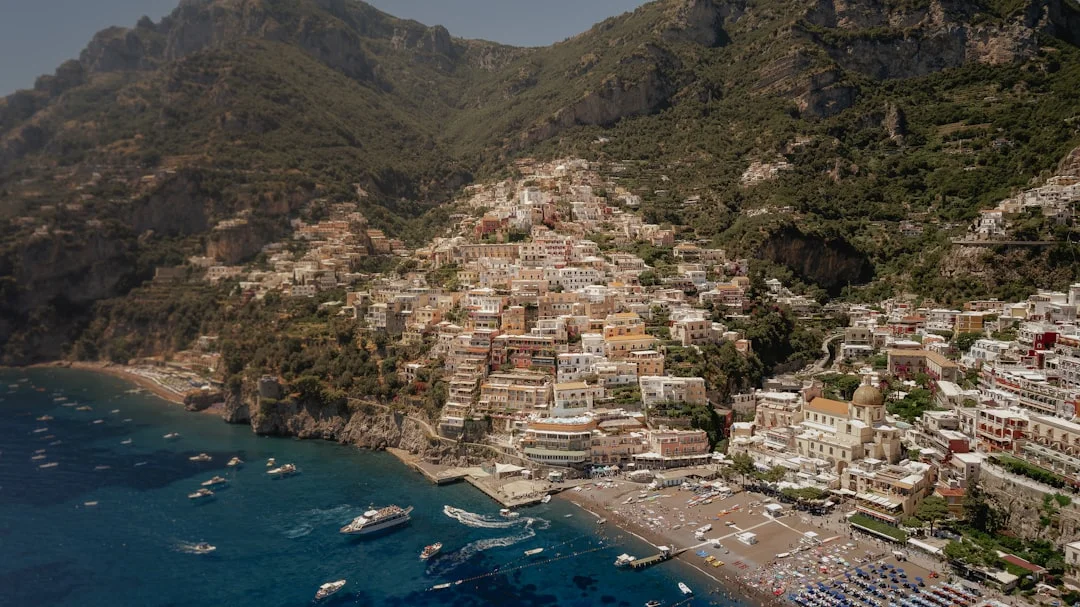 Amalfi harbor entrance with small basin, tour boats, and yachts maneuvering