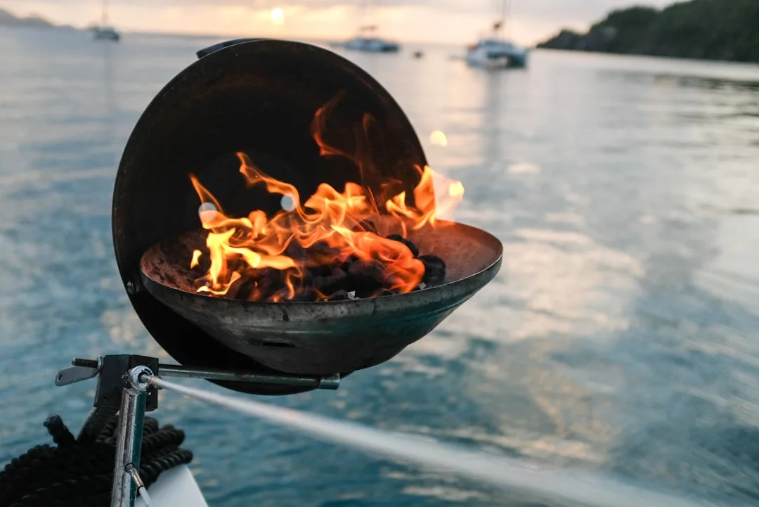 A well-used sailboat galley with gimbaled stove, pot restraints, and labeled shutoffs